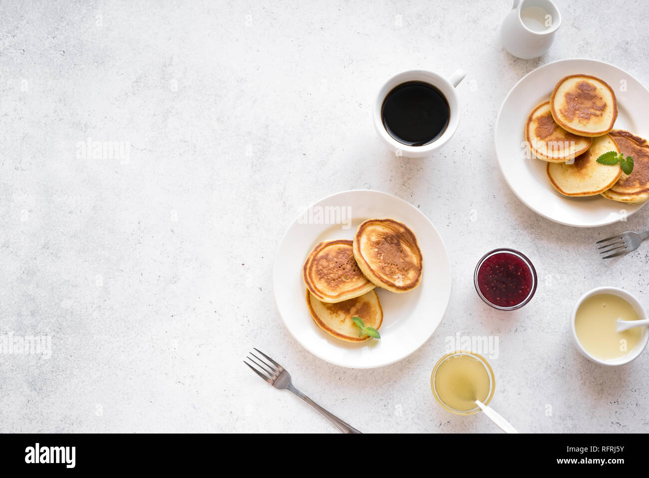 Pfannkuchen zum Frühstück. Hausgemachte Pfannkuchen mit verschiedenen Toppings, Marmelade, Honig und Kaffee - Frühstück für Zwei, Wochenende Familie Frühstück, Ansicht von oben, Kopieren s Stockfoto