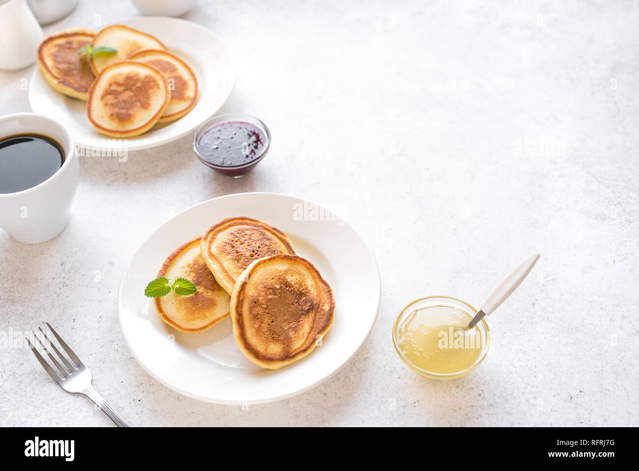 Pfannkuchen zum Frühstück. Hausgemachte Pfannkuchen mit verschiedenen Toppings, Marmelade, Honig und Kaffee - Frühstück für Zwei, Wochenende Familie Frühstück, Ansicht von oben. Stockfoto