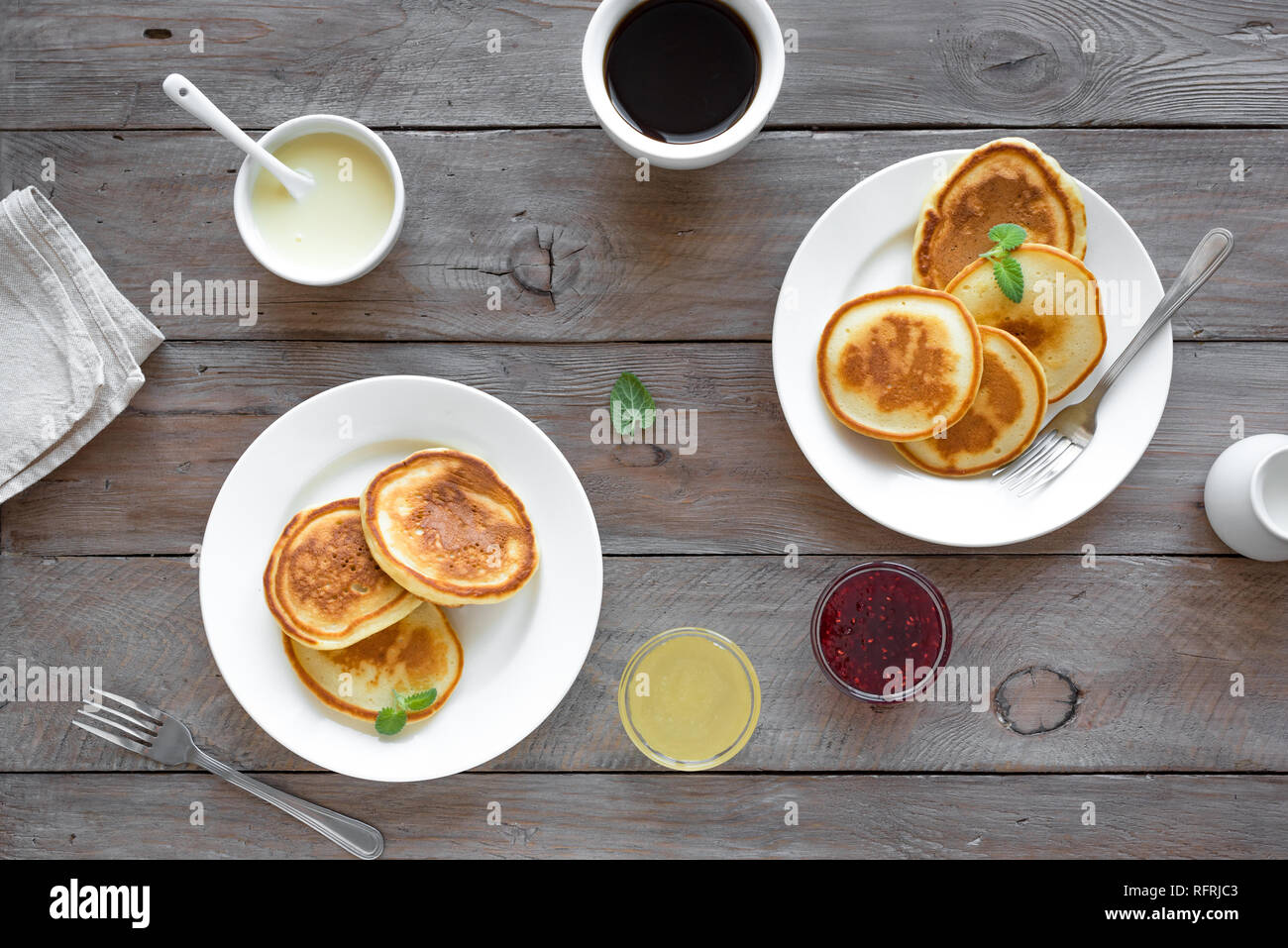 Pfannkuchen zum Frühstück. Hausgemachte Pfannkuchen mit verschiedenen Toppings, Marmelade, Honig und Kaffee - Frühstück für Zwei, Wochenende Familie Frühstück, Ansicht von oben. Stockfoto