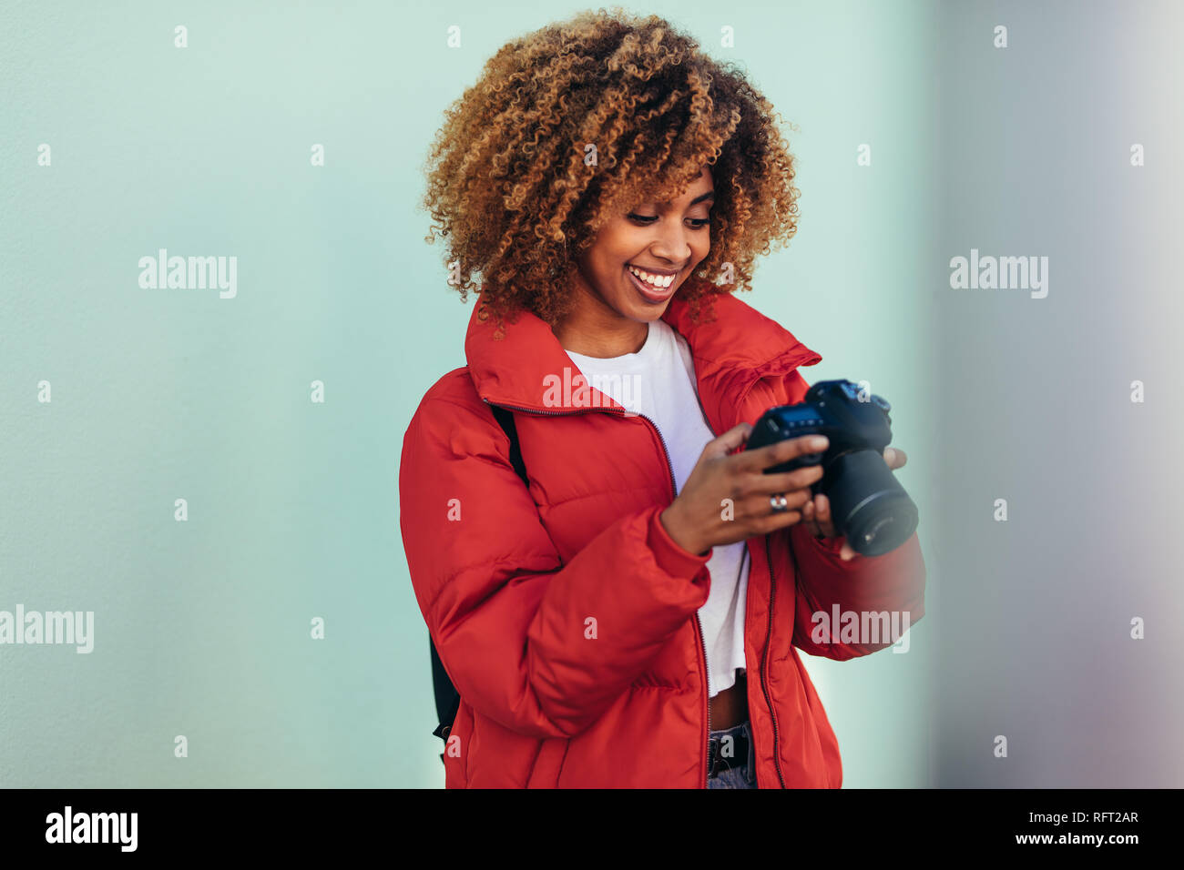 Lächelnd afro-amerikanische Frau im Urlaub an Ihrer Kamera auf der Suche nach einem Foto. Weibliche Tourist, Fotos stehen im Freien. Stockfoto