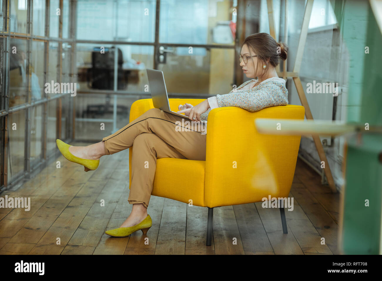 Dunkelhaarige Geschäftsfrau in Nizza bequem im Sessel sitzt Gelb Stockfoto