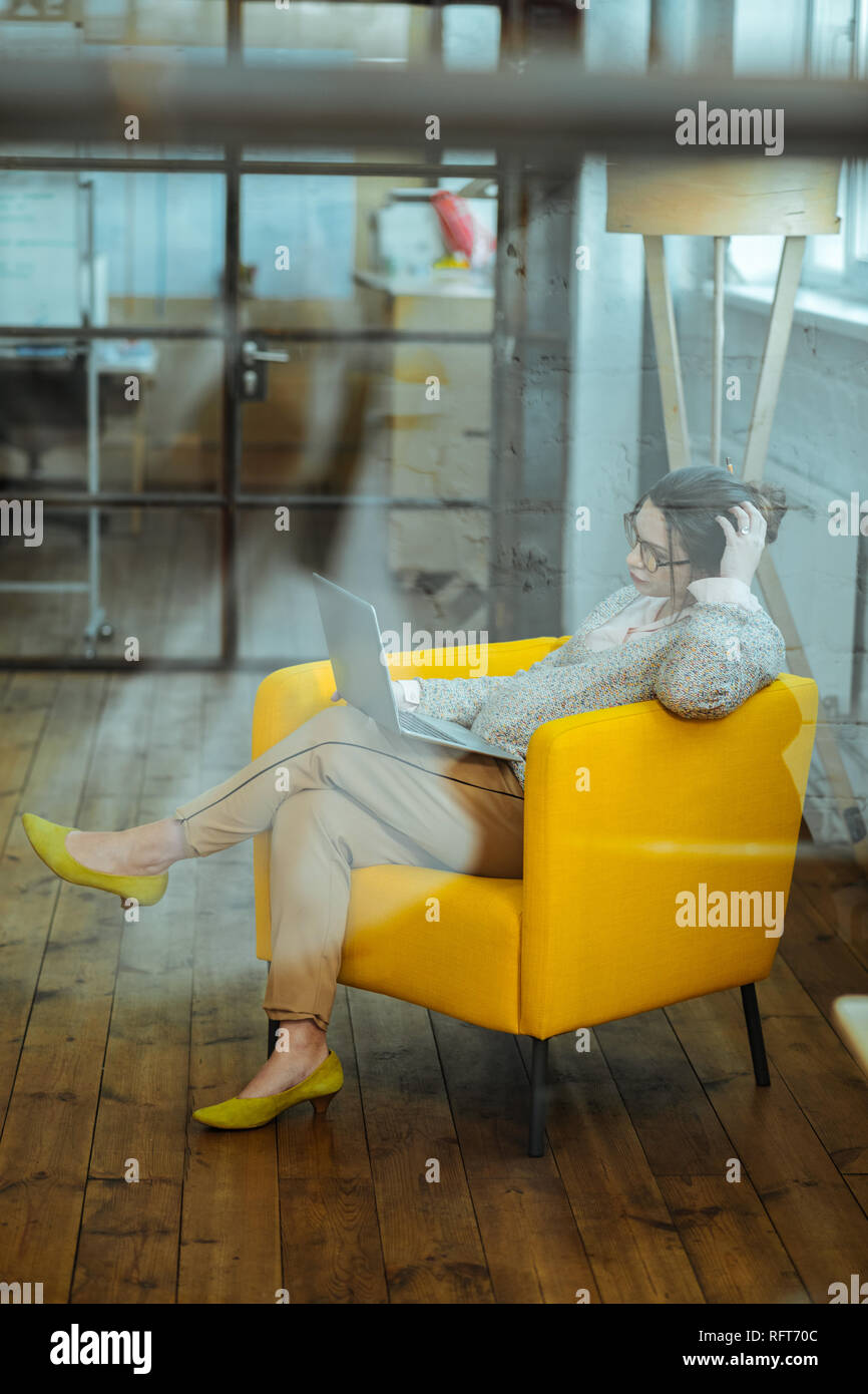 Geschäftsfrau, sitzen in bequemen Sessel während der Arbeit am Laptop Stockfoto