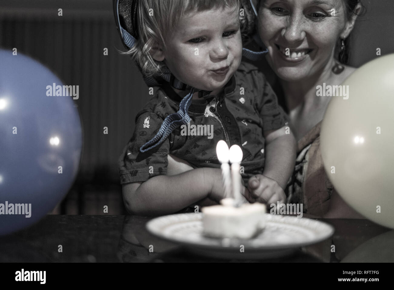 Das Porträt einer Happy Birthday Boy und seine lächelnde Mutter Abblasen des Geburtstag Kerzen. Luftballons im Vordergrund. Stockfoto