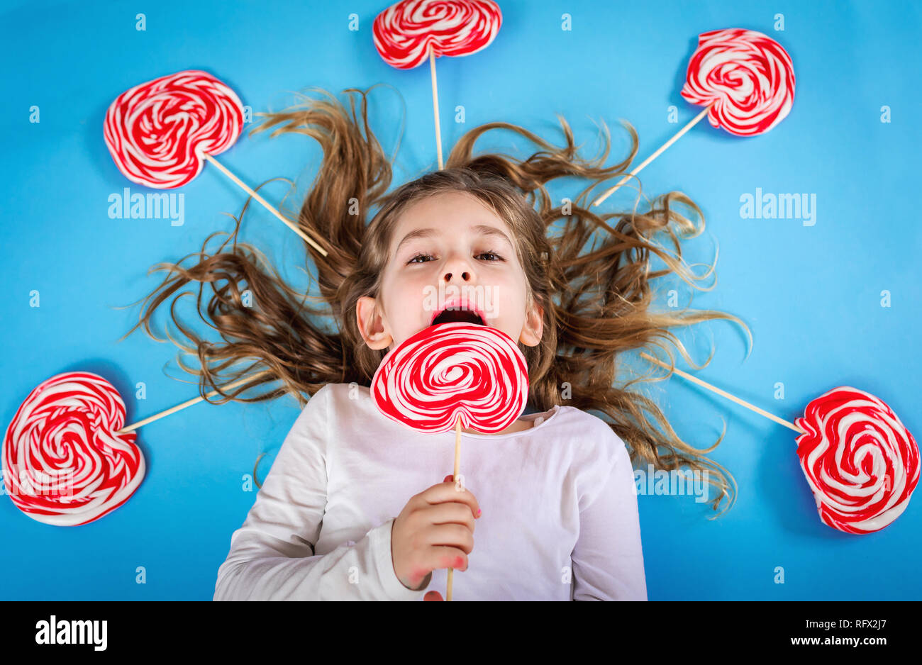 Kleines Mädchen mit Lollipop auf blauem Hintergrund Stockfoto