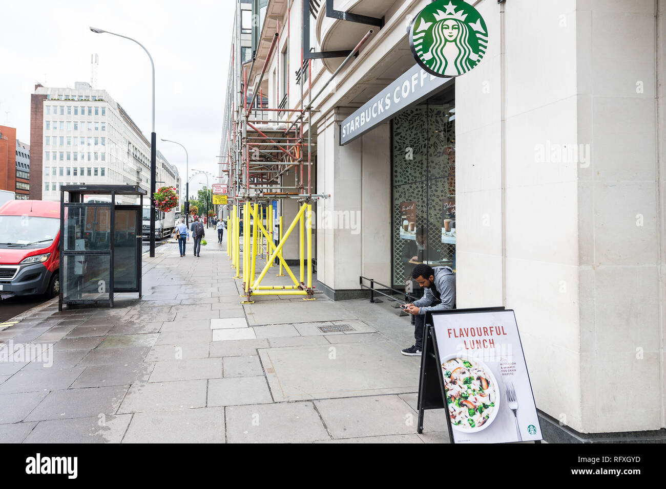London, Großbritannien - 12 September 2018: Nachbarschaft von Westminster an der Victoria Street mit Personen sitzen auf bürgersteig von Starbucks Cafe Restaurant Zeichen entr Stockfoto