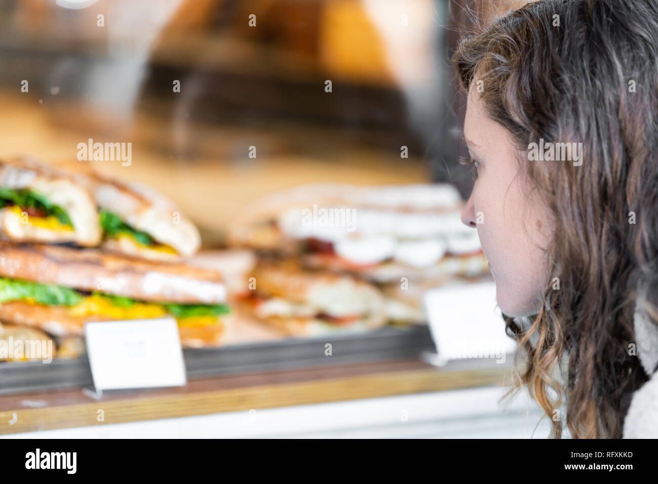 Nahaufnahme der Frau bei Anzeige von Sandwiches hinter Glas in Cafe Restaurant Storefront suchen Stockfoto