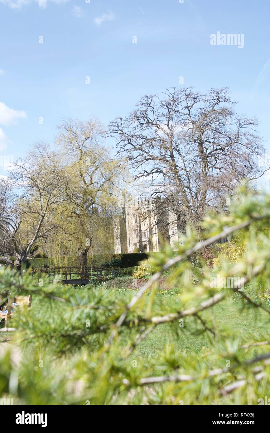 Außerdem befinden sich das Hever Castle, Kent, an einem sonnigen Frühlingstag, der von Bäumen und mit jungen angehenden grüne Zweige im Vordergrund gerahmt, mit dem blauen Himmel zu Kontrast Stockfoto