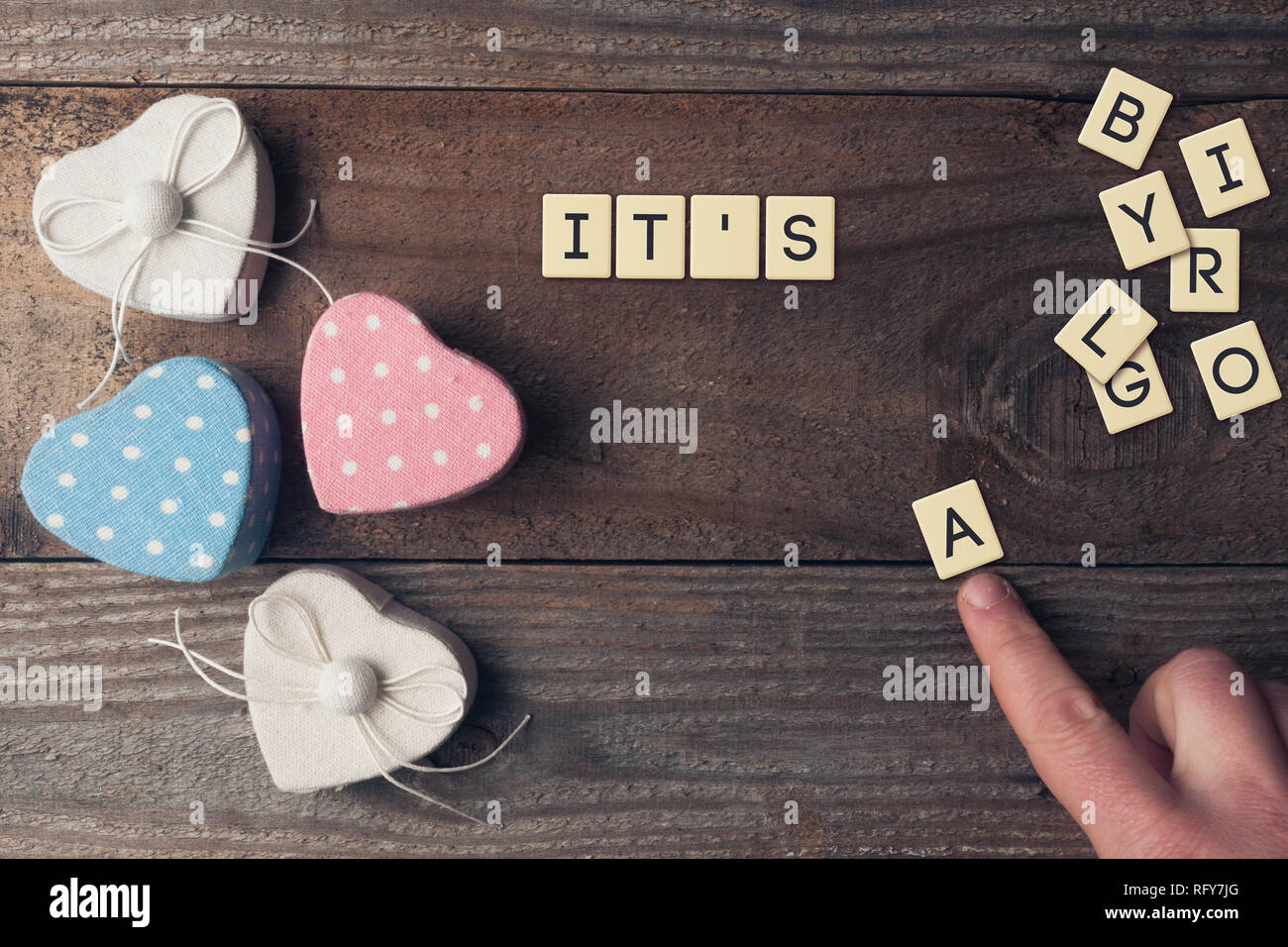 Baby Mitteilungstafel: Mann verfassen den Text 'Es ist ein... Auf hölzernen Tisch entlang zwei Rosa und Blau farbige Boxen Stockfoto