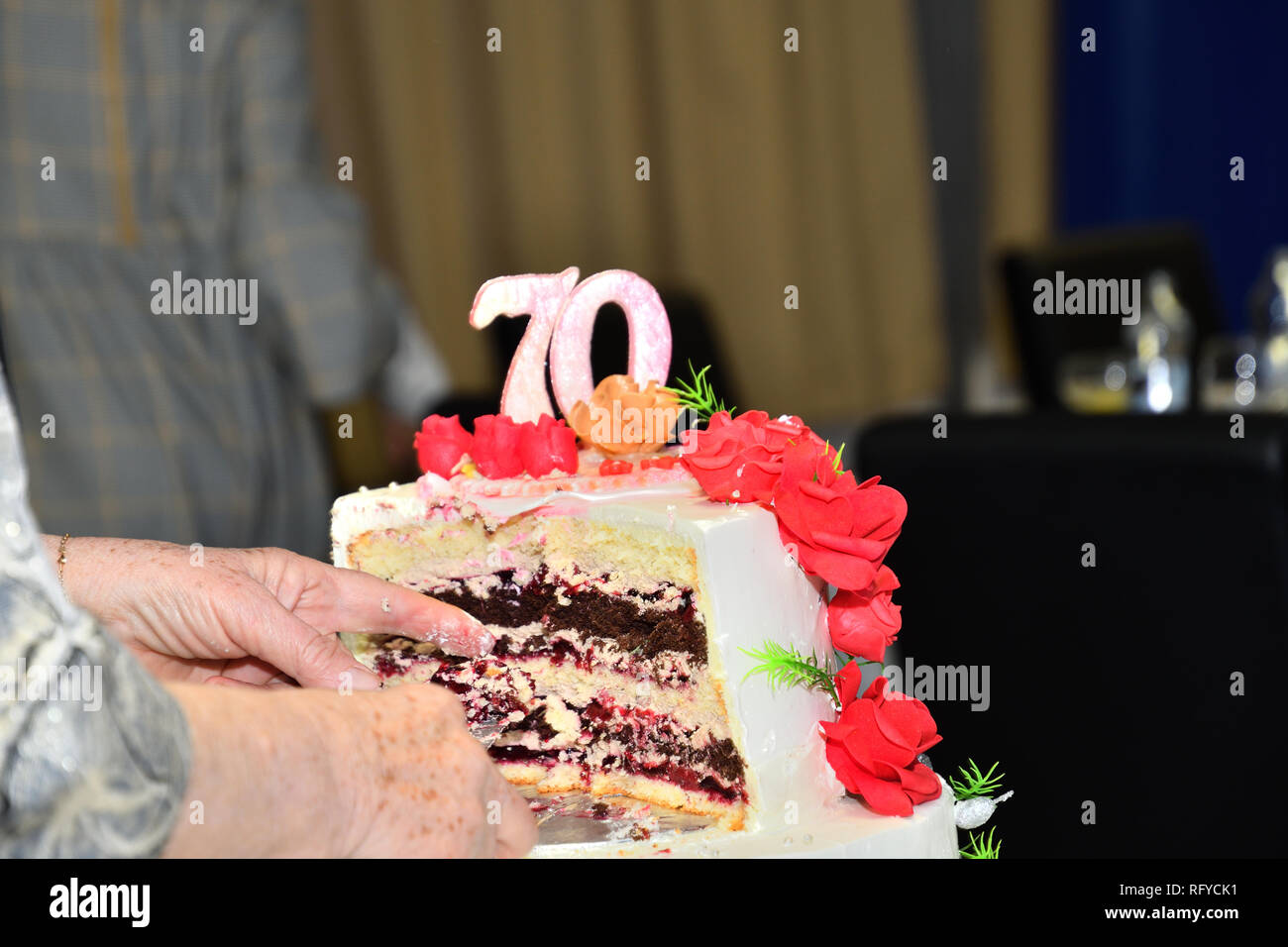 Kuchen Schneiden mit einem Messer zu 70 Geburtstage feiern. Stockfoto