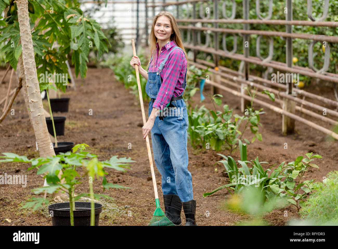 Stilvolle Mädchen in kariertes Hemd und insgesamt mit einem Rechen im Garten Stockfoto