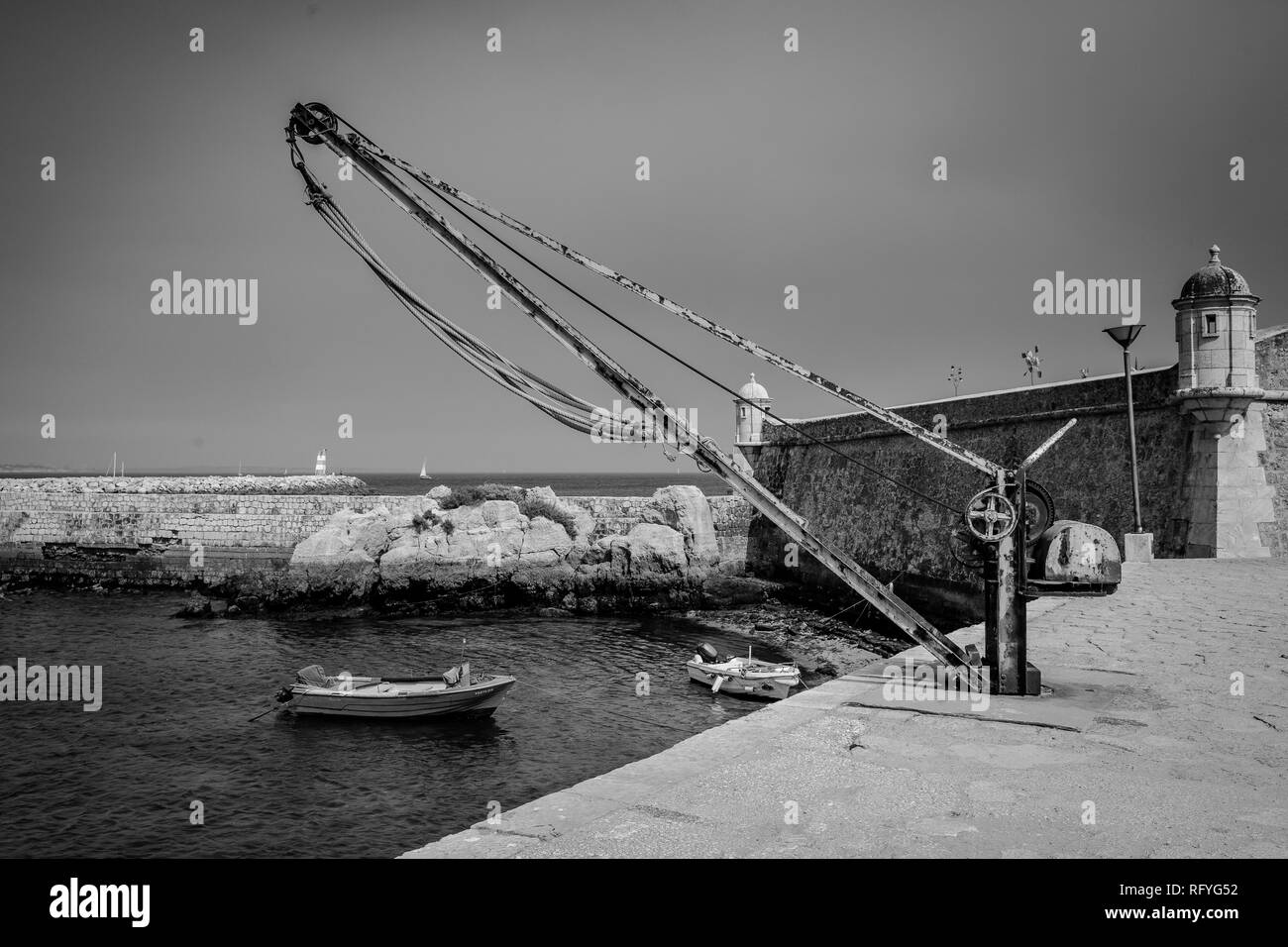 Schwarz-weiß Foto von einem kleinen Dock und Boot im Forte da Ponta da Bandeira, Portugal. Stockfoto