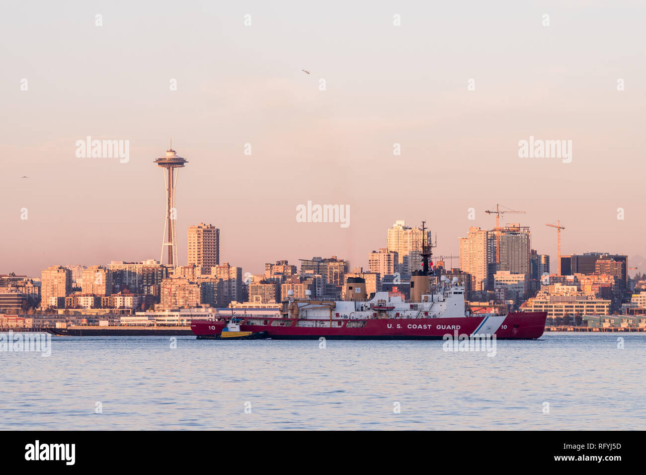 Küstenwache Boot in der Elliott Bay mit Sonnenuntergang über der Innenstadt von Wolkenkratzern in Seattle, Washington, USA. Stockfoto