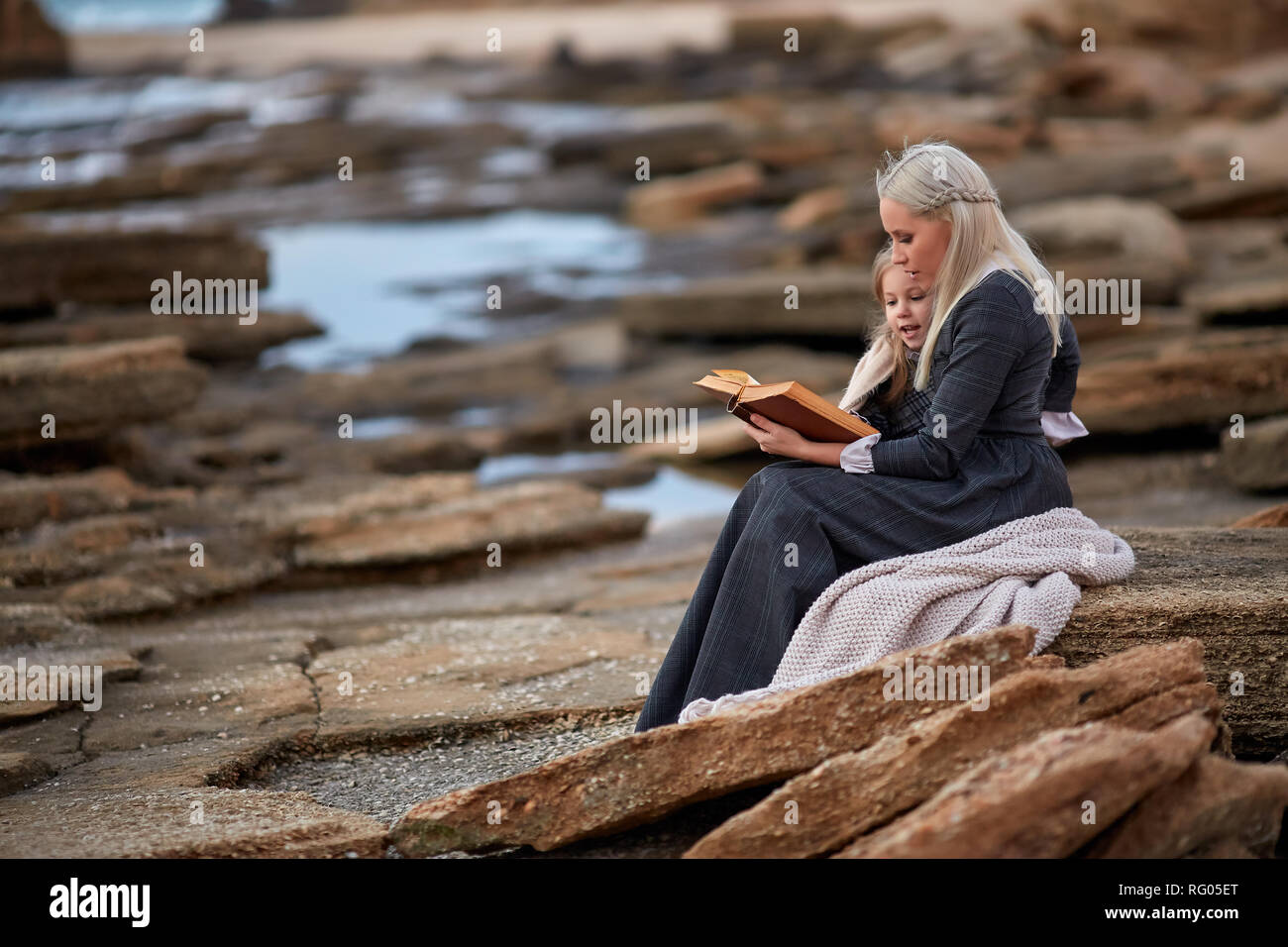 Frau mit Mädchen lesen Buch über Meer Stockfoto