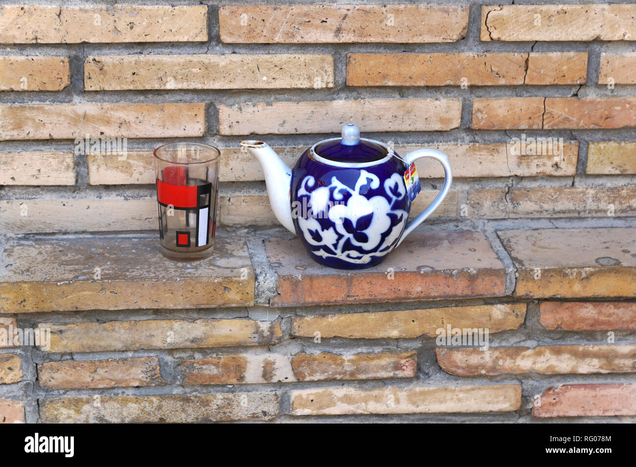 Teekannen mit Glas auf Ziegelwand, Taschkent, Usbekistan Stockfoto