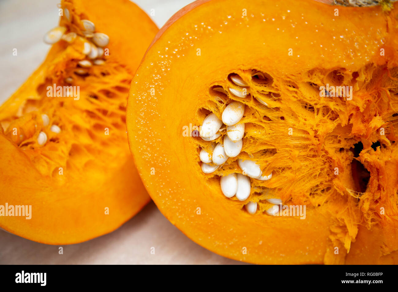 Leckere, gesunde und fleischigen Gemüse - saftig, hell orange Kürbis in einem Schnitt mit Samen in Nahaufnahme, neben einem Schneiden Schneiden. Kürbis oval mit einer harten Kruste geprägt. Stockfoto