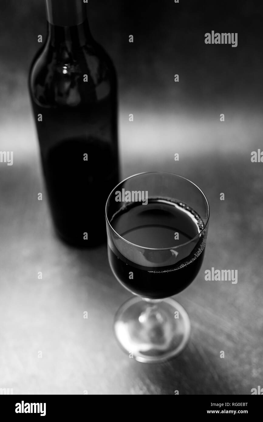 Glas intensiv rot Wein und Flasche auf dunklem Hintergrund, Konzept der eleganten oder teuren Wein Auswahl Stockfoto