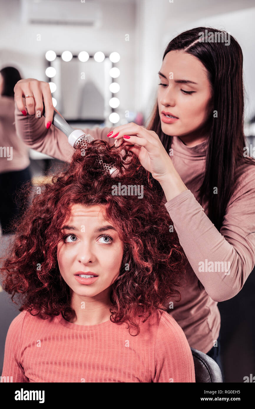 Schön ernste Frau tun Professional Hair Styling Stockfoto