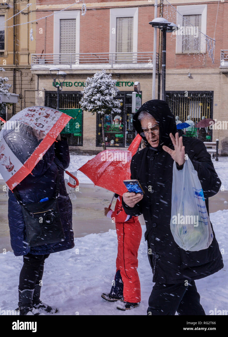 Man Walking in der Straße während des Schneesturms am Smartphone suchen, Menschen, die hinter ihm stehen, Schirme, Avezzano, Abruzzen, Italien, Europa Stockfoto
