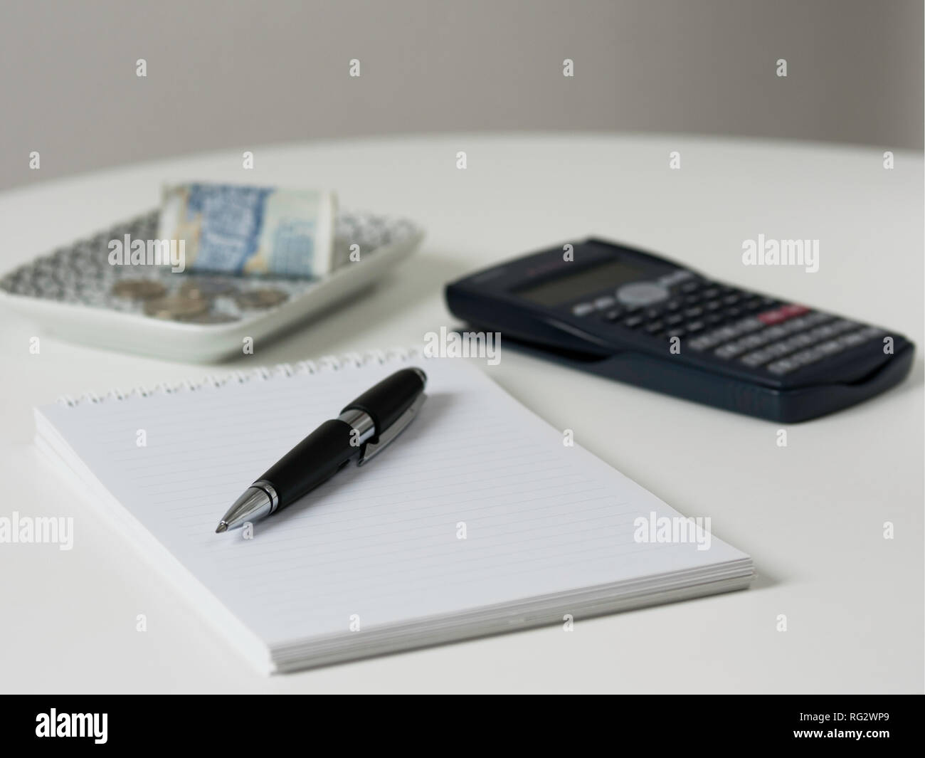 Geld, Stift, Notebook und Rechner auf einem Schreibtisch Stockfoto
