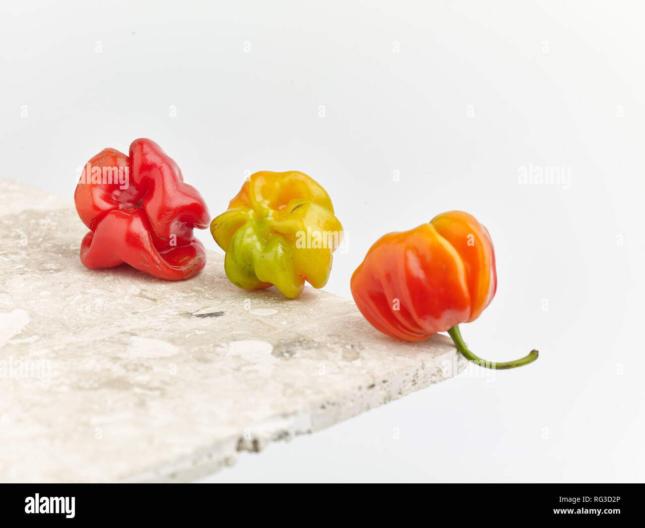 Scotch Bonnet Pepper und gescheckte Marmor Oberfläche gegen hellen Hintergrund. Essen Foto Stockfoto