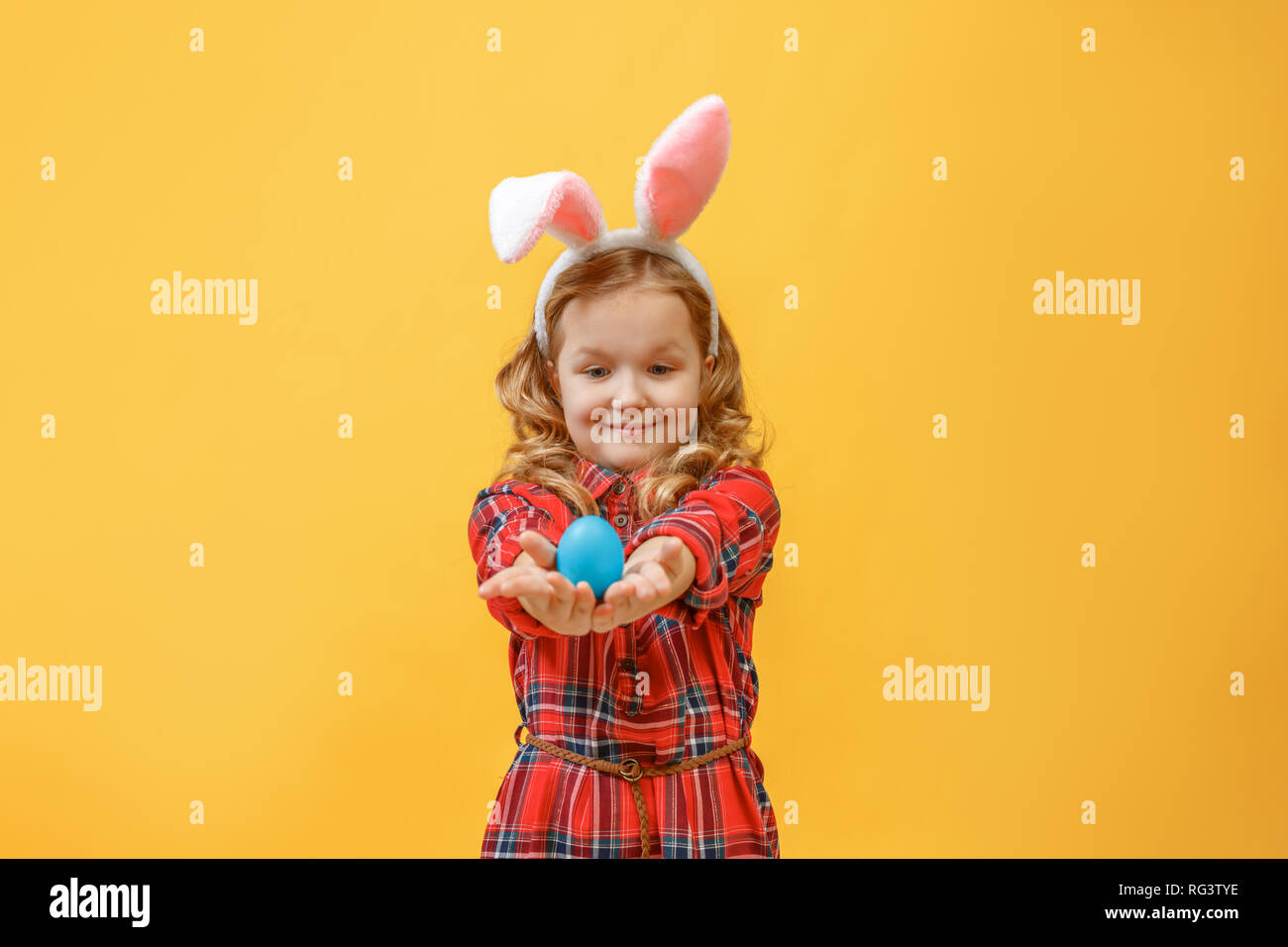 Fröhliche kleine Kind Mädchen mit Hasenohren mit einem Osterei auf einen farbigen Hintergrund. Stockfoto