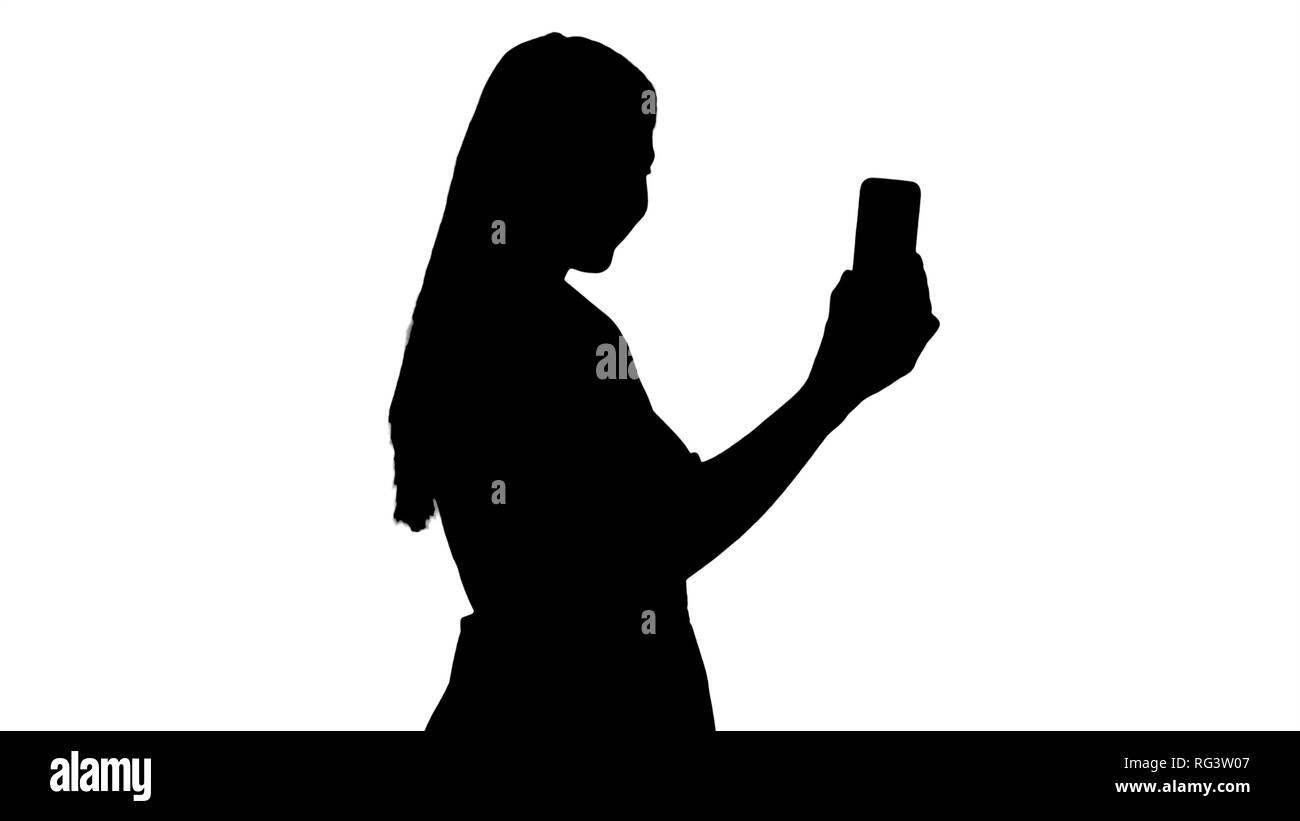Mittellange Aufnahme von der Seite. Silhouette Frau im rosa Kleid, mit Ihrem Smart Phone. Professionelle Aufnahme in 4K-Auflösung. 005. Sie können es verwenden, Stockfoto