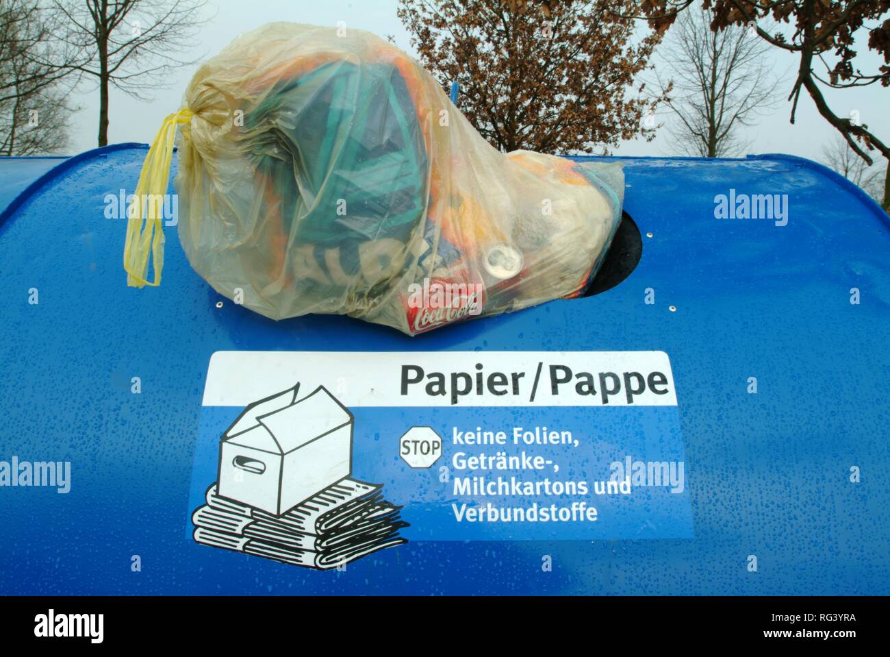 DEU, Deutschland, Mönchengladbach: Miss ein Altpapiercontainer, durch eine Tasche mit Hausmüll. Stockfoto