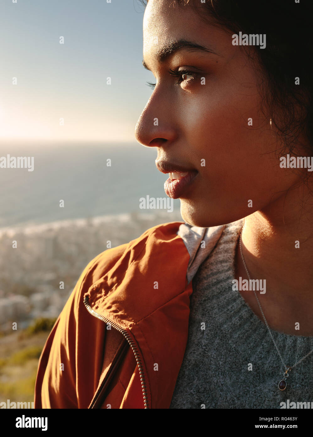 Close up Portrait von wunderschönen afrikanischen Frau in Pullover und Jacke stehen draußen und weg schauen. Gesicht der jungen afrikanischen Frauen weg schauen übertreffen Stockfoto