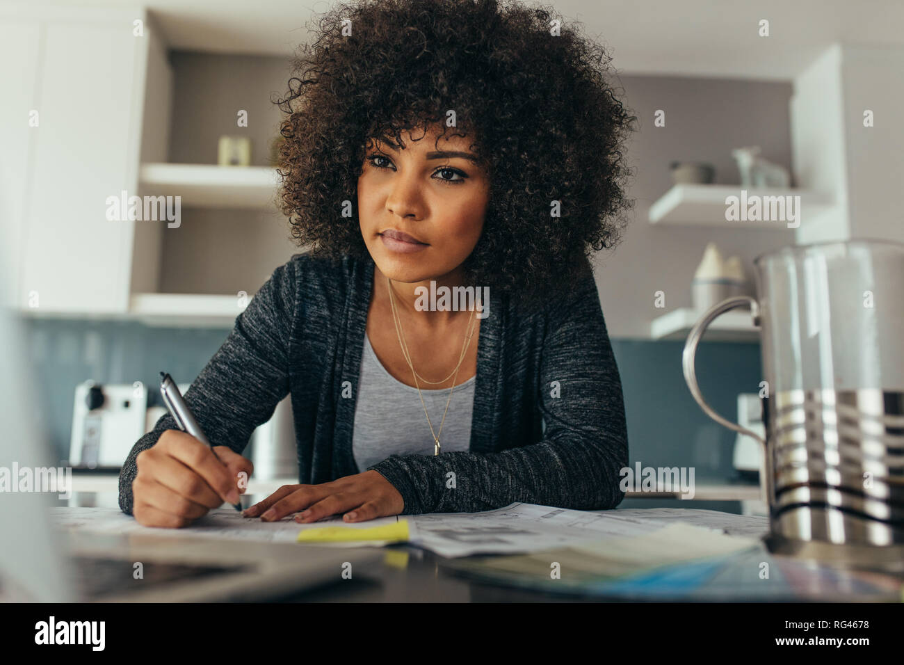 Afrikanische Frau sitzt an ihrem Arbeitstisch suchen und Bildschirm während der Vorbereitung einer Konstruktion einer Blaupause. Junge weibliche Architekten auf neue Arbeiten Stockfoto