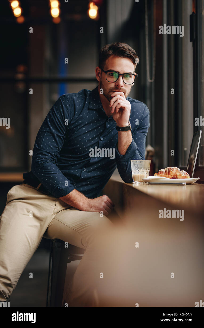 Freiberuflicher Geschäftsmann in einem Restaurant mit Speisen und Laptop vor. Mann sitzt in einem Café mit Snacks und Laptop und Denken. Stockfoto