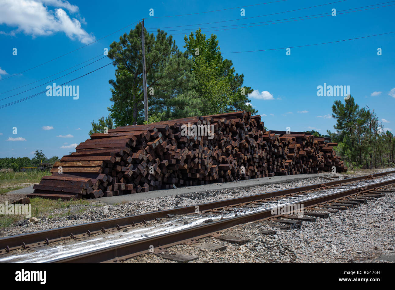 Einen großen Stapel von nicht verwendeten Bahnschwellen neben den Gleisen gestapelt. (Hohe Sättigung) Stockfoto