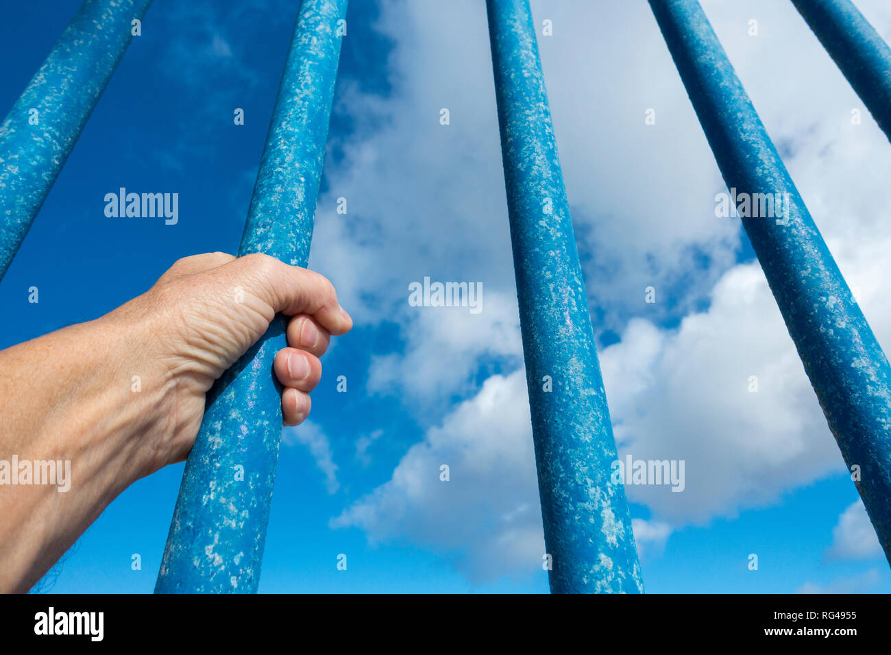 Hinter Gittern gegen den blauen Himmel Person. Asyl, Grenzkontrollen, illegale Einwanderung, Gefängnis ... Konzept. Stockfoto