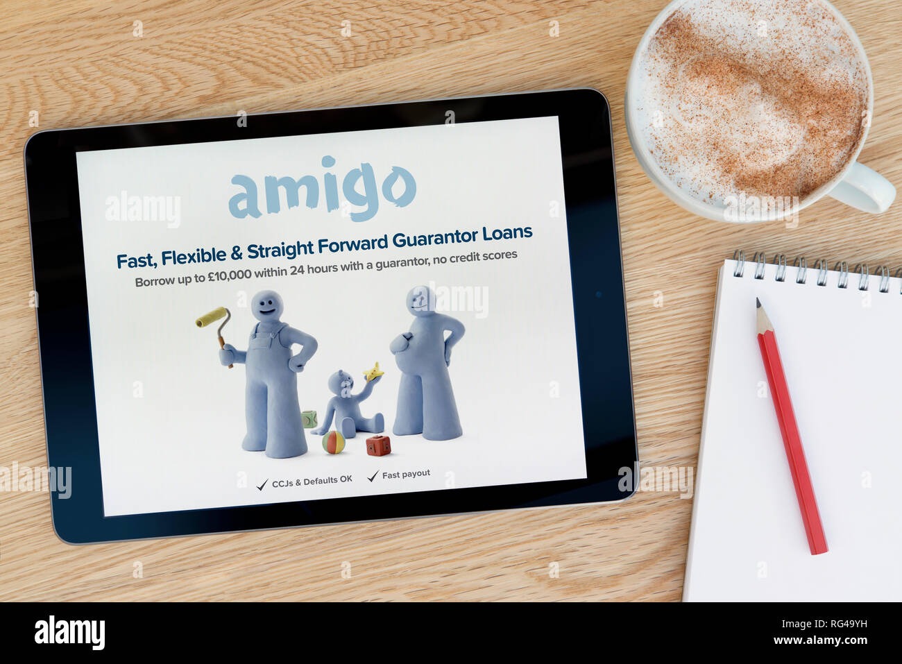 Die Amigo Darlehen website Funktionen auf einem iPad Tablet Gerät, das auf einem Tisch liegt neben einem Notizblock (nur redaktionelle Nutzung). Stockfoto