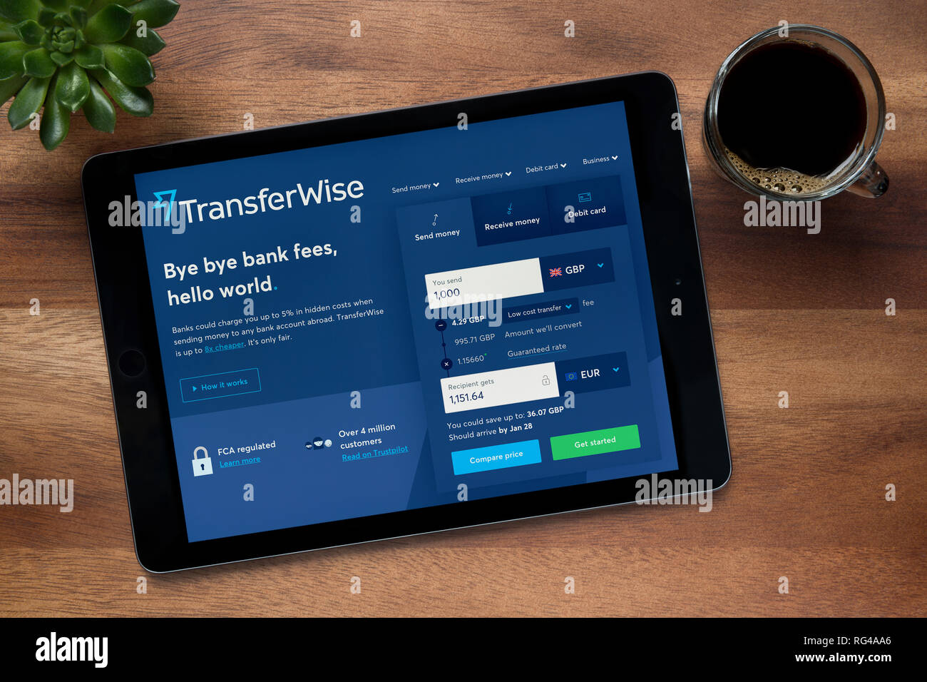 Die Website von Transferwise ist auf einem iPad Tablet gesehen, auf einer hölzernen Tisch zusammen mit einem Espresso und einem Haus Anlage (nur redaktionelle Nutzung). Stockfoto