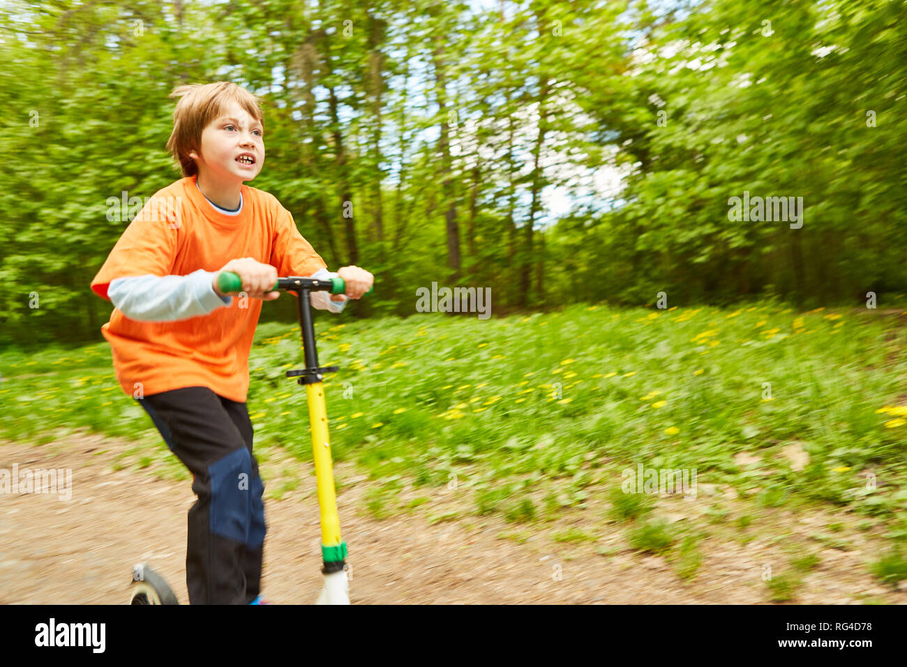 Kind auf einem Roller unterwegs in der Natur im Sommer Ferien Stockfoto