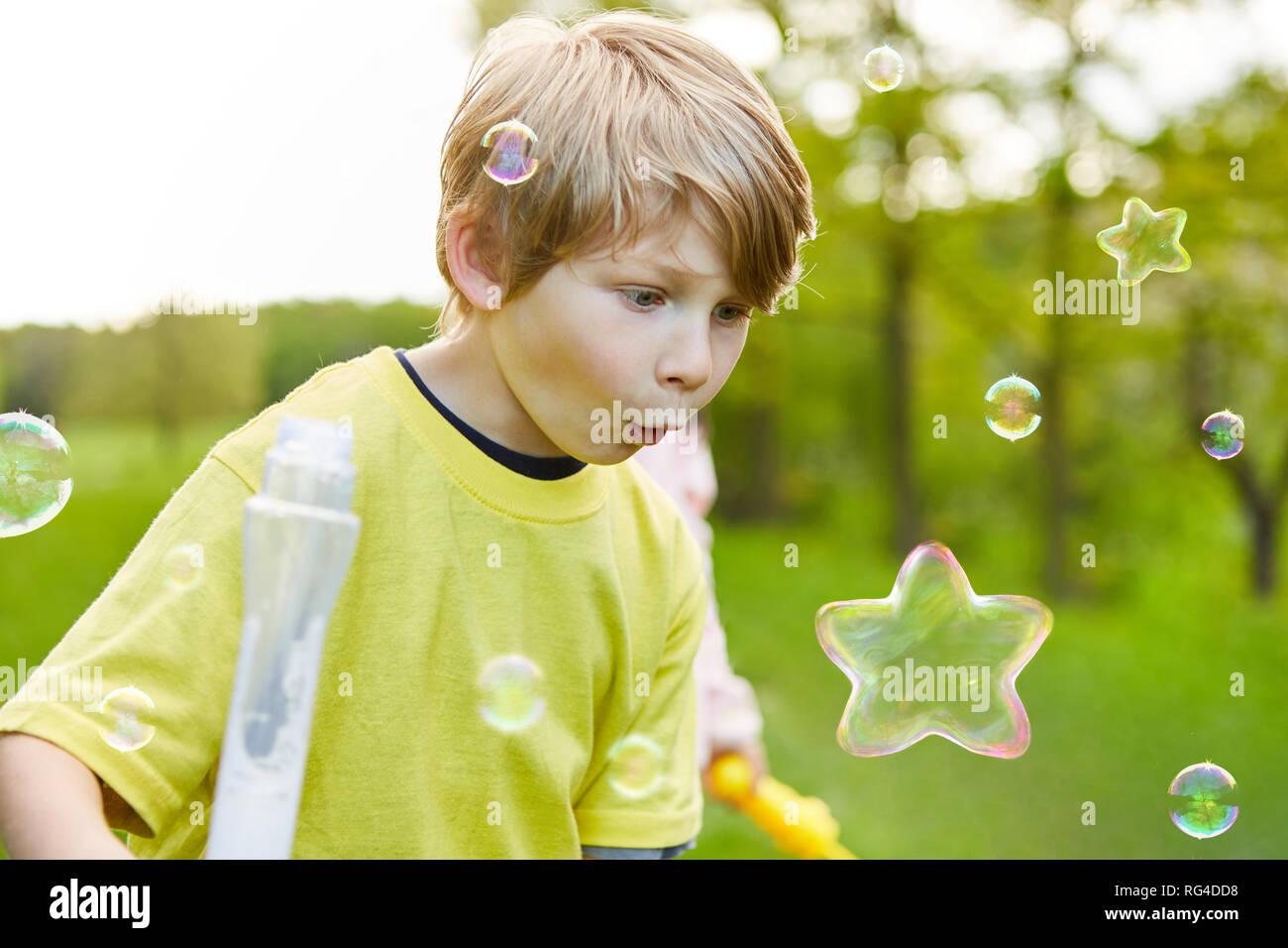 Kind wird von Seifenblase in Sternform im Sommer im Park begeistert Stockfoto