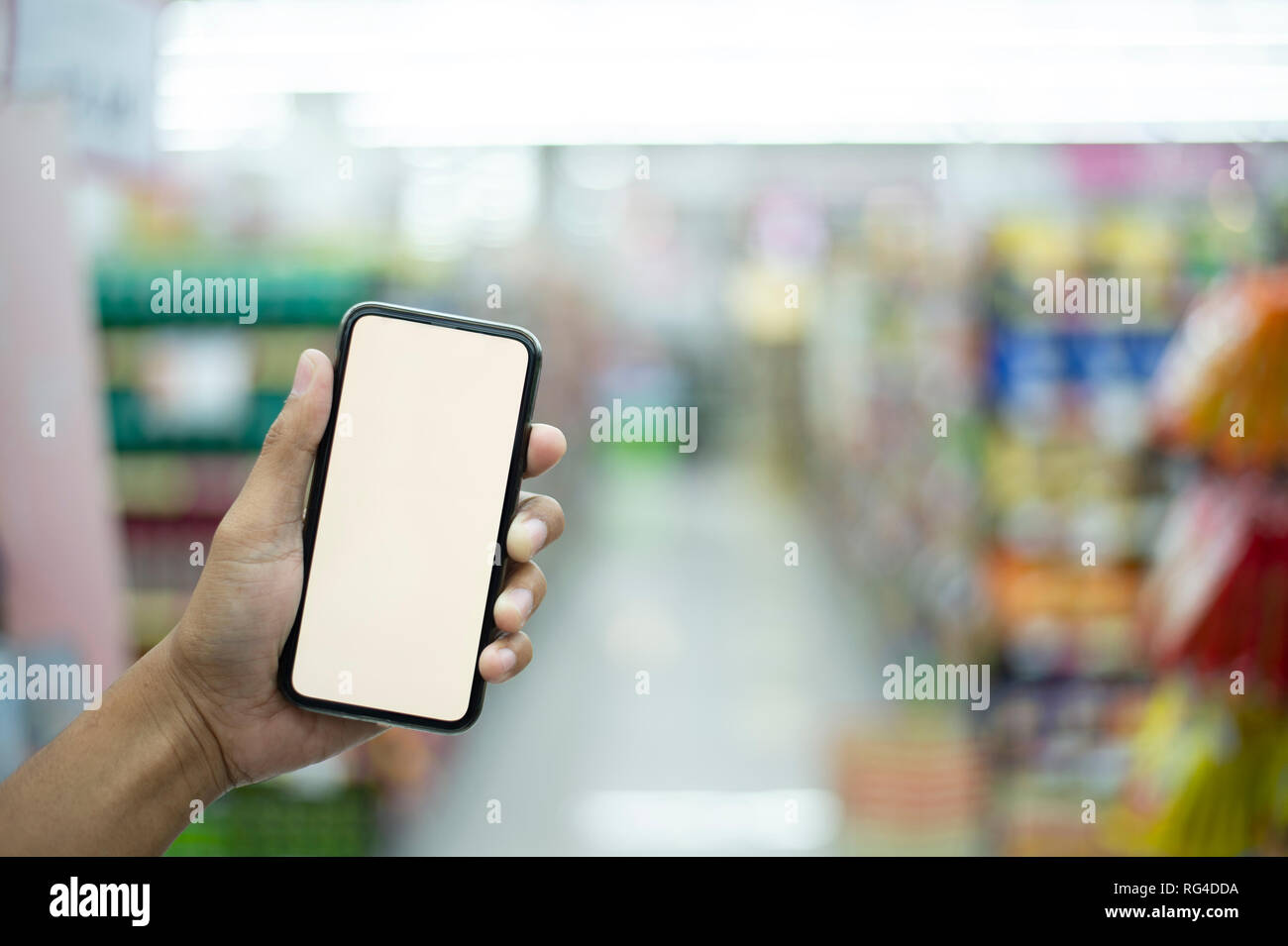 Mann tun Einkaufen im Supermarkt und Scannen eines Barcodes können Sie über ihr Smartphone, Technologie und Einzelhandel Konzept - Bild Stockfoto