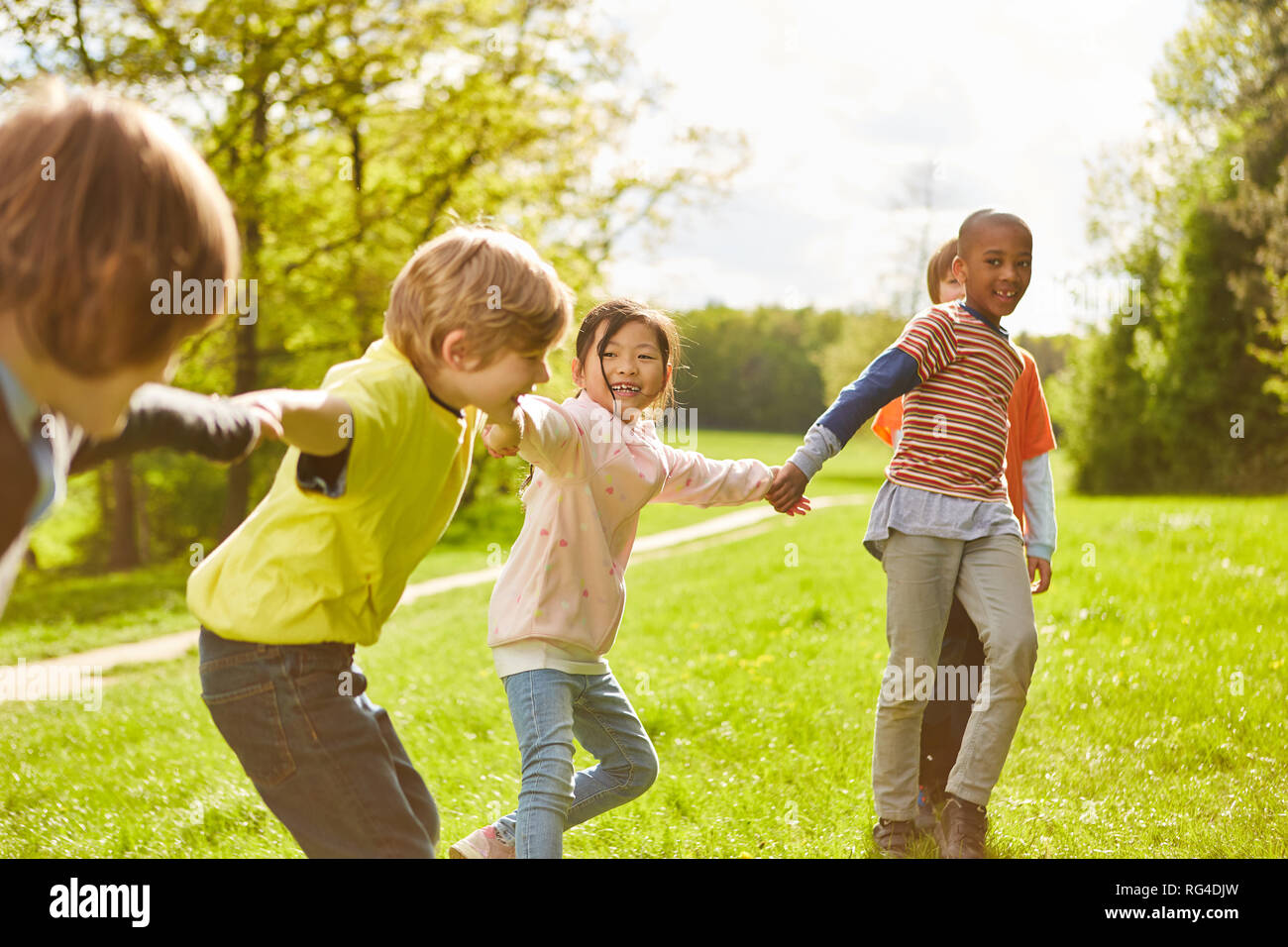 Multikulturelle Kinder Gruppe hält die Hände als Freunde auf einer Wiese Stockfoto