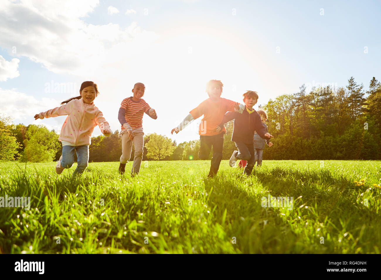 Kinder laufen und spielen auf einer Wiese im Sommer auf Kindergeburtstag Stockfoto