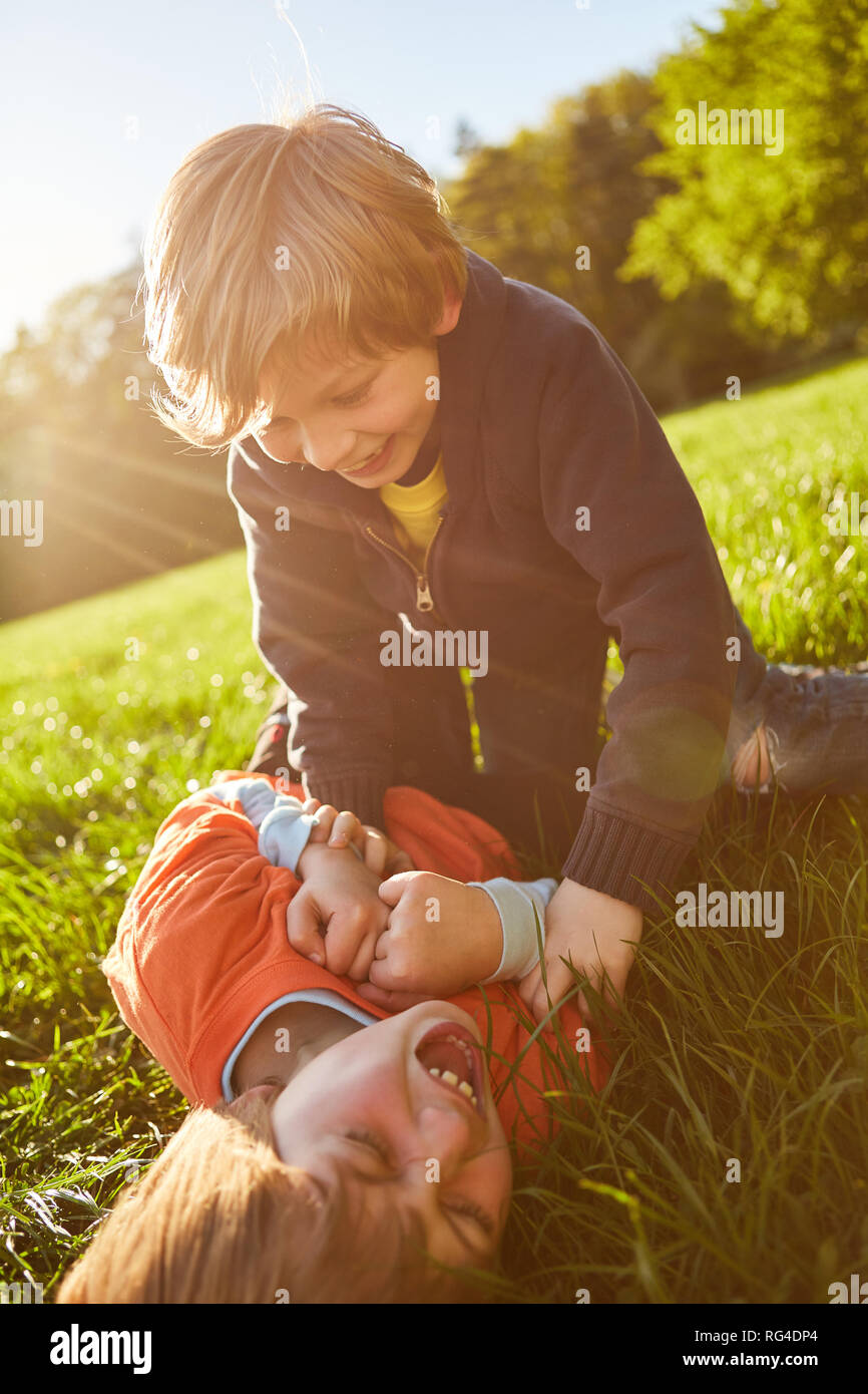 Junge ist Kitzeln sein Lachen Freundin auf einer Wiese beim Spielen in der Sonne Stockfoto