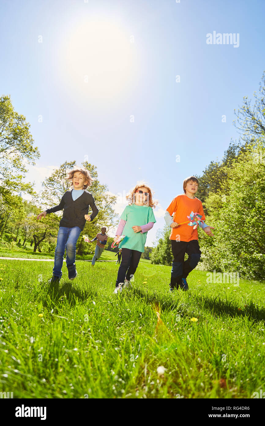 Kinder laufen im Sonnenschein über eine grüne Wiese im Sommer Camp Stockfoto