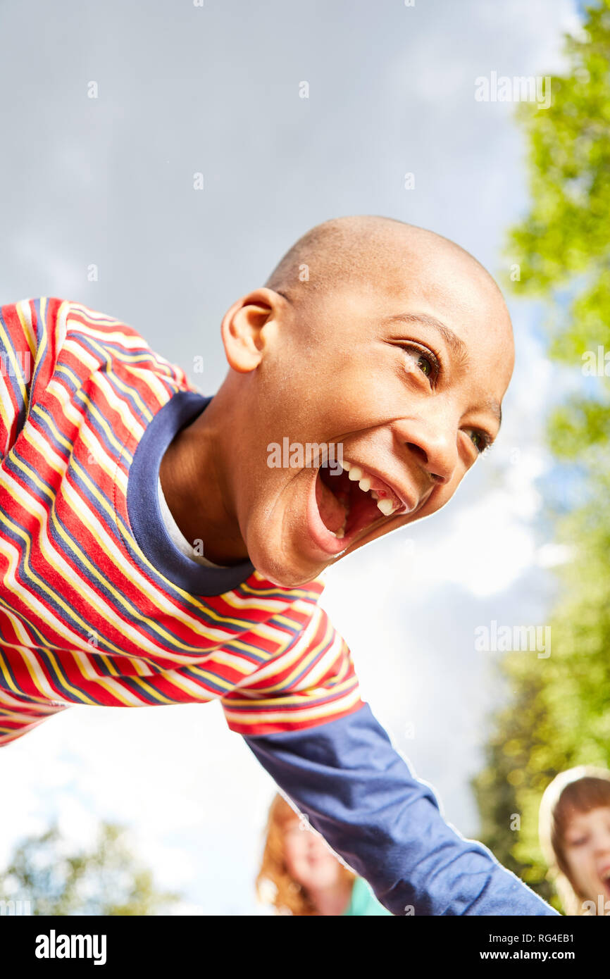 Afrikanischen Jungen spielt mit Begeisterung mit seinen Freunden im Sommer Stockfoto