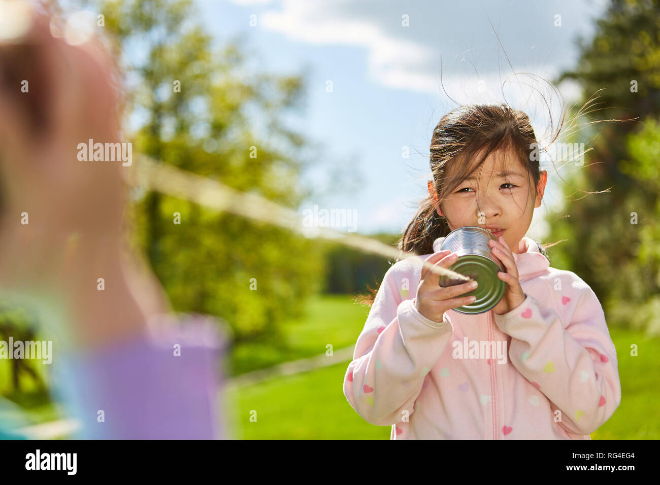 Kleine Mädchen spielen mit hausgemachten können Telefon mit Schnur in der Natur Stockfoto