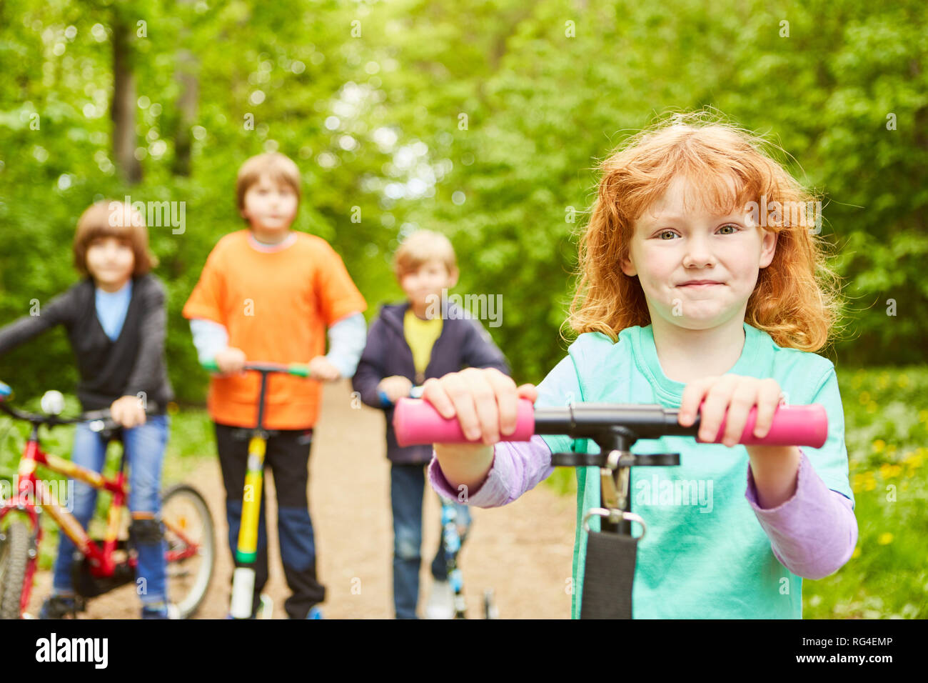 Gruppe von Kindern auf einem Fahrrad fahren mit dem Fahrrad, dem Scooter in einem Park im Sommer Stockfoto