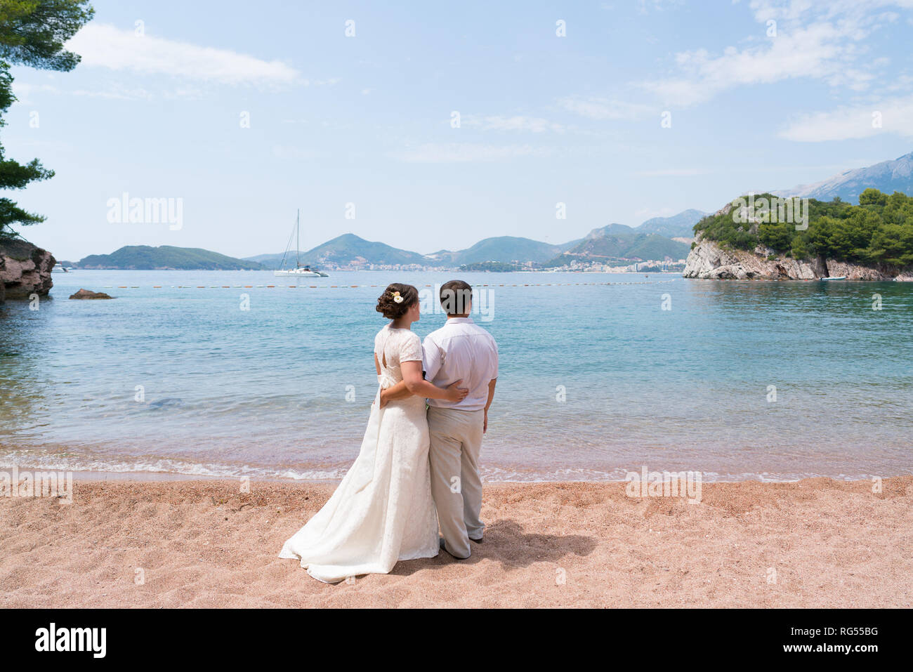 Brautpaar stand am Strand an einem sonnigen Tag und an das Meer, das Hände schauen Stockfoto