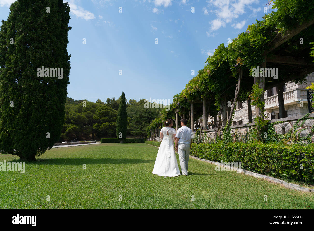 Brautpaar zu Fuß auf den Rasen an einem sonnigen Tag händchenhaltend Stockfoto