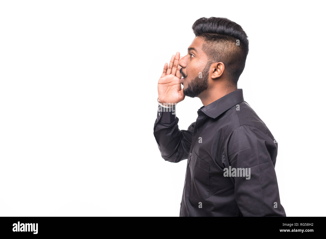 Portrait von Indischen Kerl schreit laut, Mund und Hand umschloss Neben. Asiatischer Mann stehend auf einfachen Hintergrund mit Schatten und Kopieren. Stattliche m Stockfoto