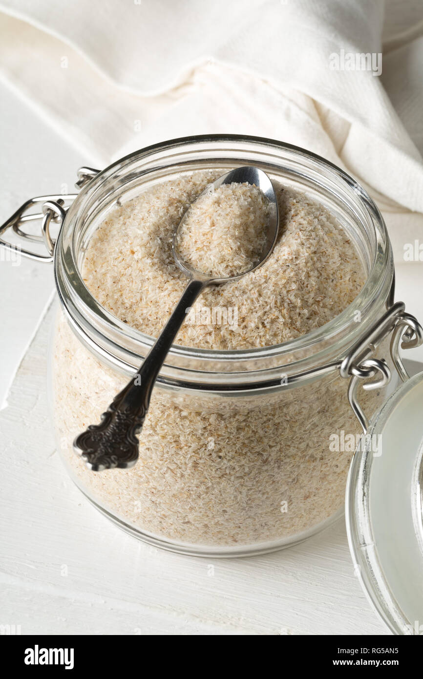 Haufen psyllium husk auch genannt Isabgol in Glas Glas mit metalllöffel auf weißem Hintergrund. Psyllium husk auch genannt Isabgol ist Faser abgeleitet Stockfoto