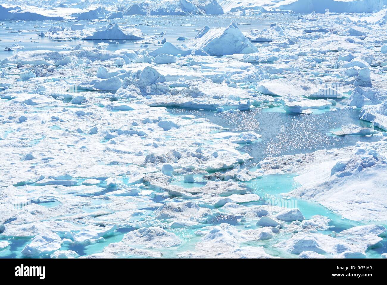 Ilulissat, Grönland, Juli | UNESCO-Weltkulturerbe | Diskobucht Kangia Icefjord | riesige Eisberge im blauen Meer an einem sonnigen Tag - globale Erwärmung Stockfoto