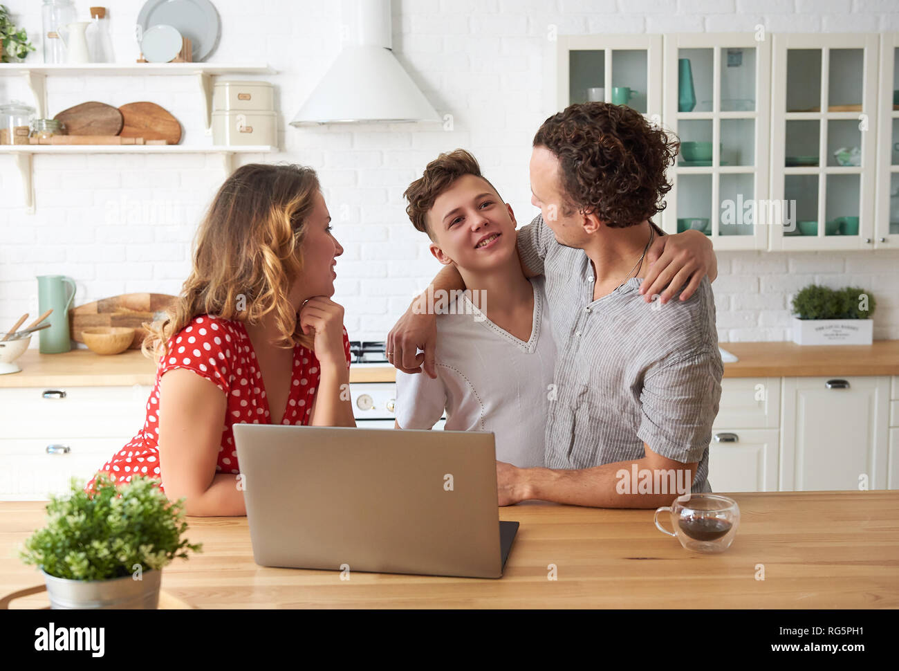 Glückliche Familie mit Laptop in der Küche. Sohn, Mutter und Vater zusammen. Stockfoto